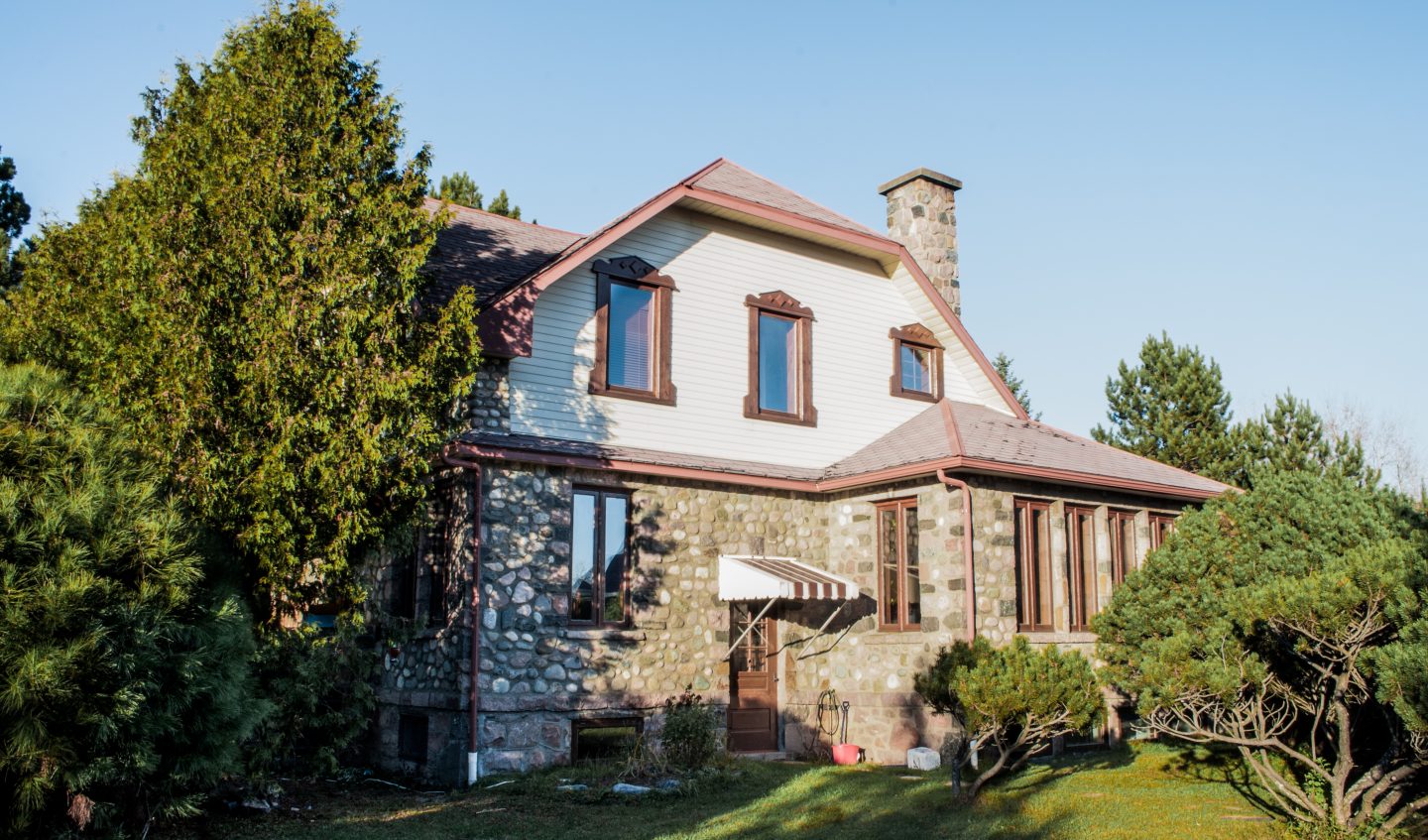 maison de style Cottage anglais construite en 1942 avec murs extérieurs en pierres des champs et déclin, situé à St-Bruno-de-Guigues au Témiscamingue